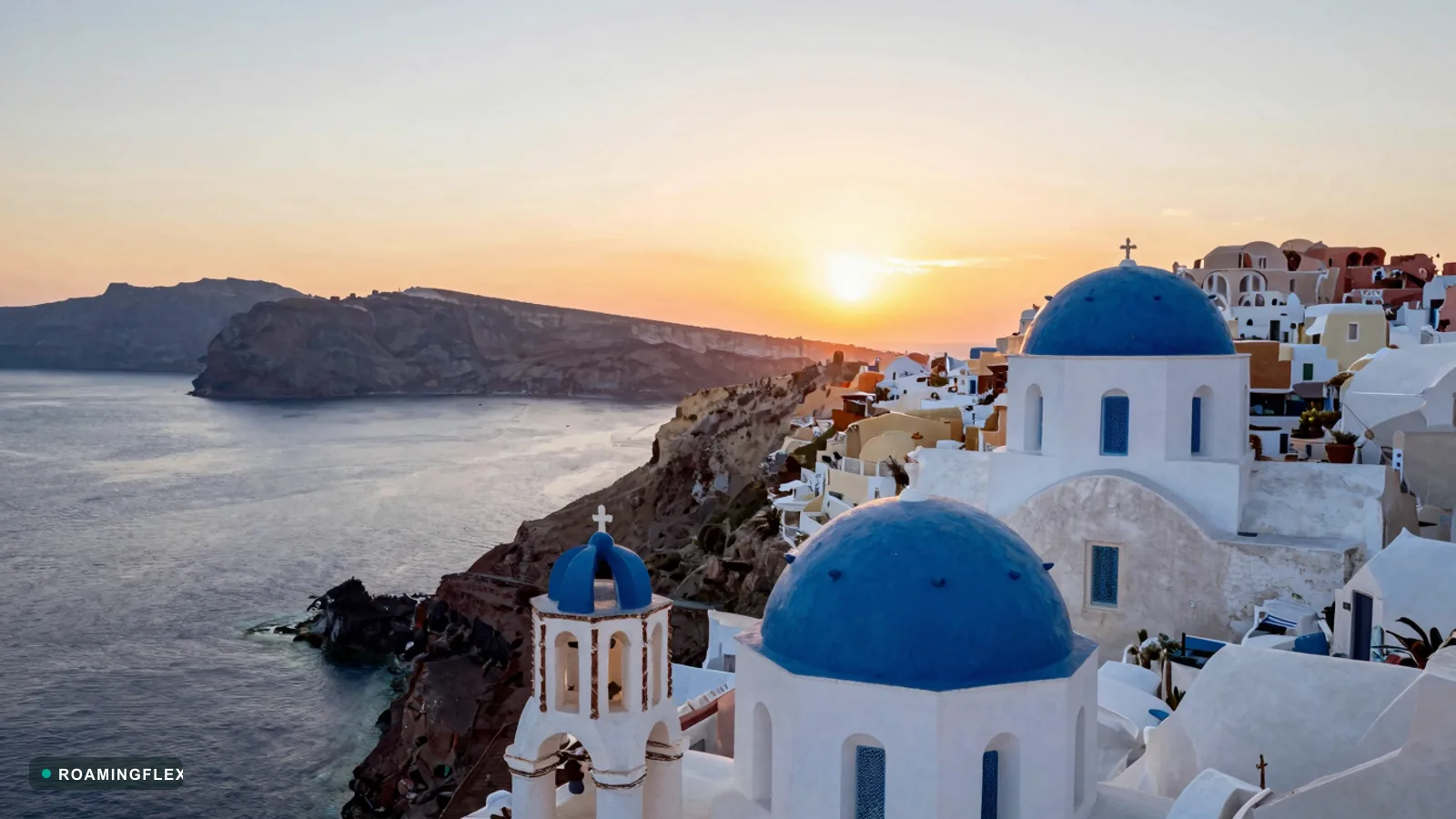 Whitewashed buildings and blue domes of Oia at sunset in Santorini, Greece