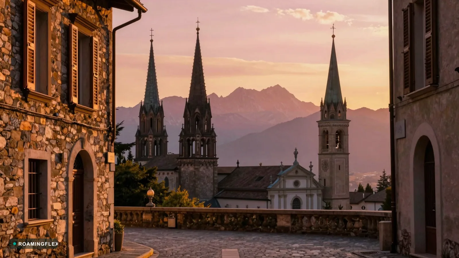 European cityscape at golden hour with cathedral spires and alpine mountains